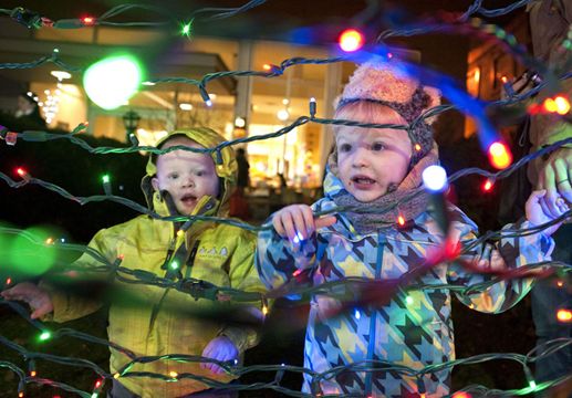 Aden Moir, right, and Ethan Nutt play with the Christmas tree lights Thursday night during the Light Up the Riverside holiday event at Mustard Seed Parkette.