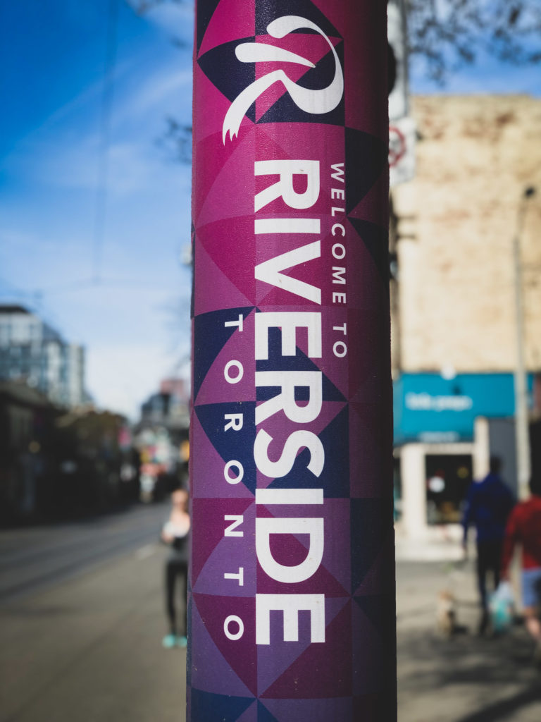 The Riverside BIA brand today (since 2018) seen on the street with vibrant blues, purples and pinks on hydro pole wraps along Queen Street East, Toronto