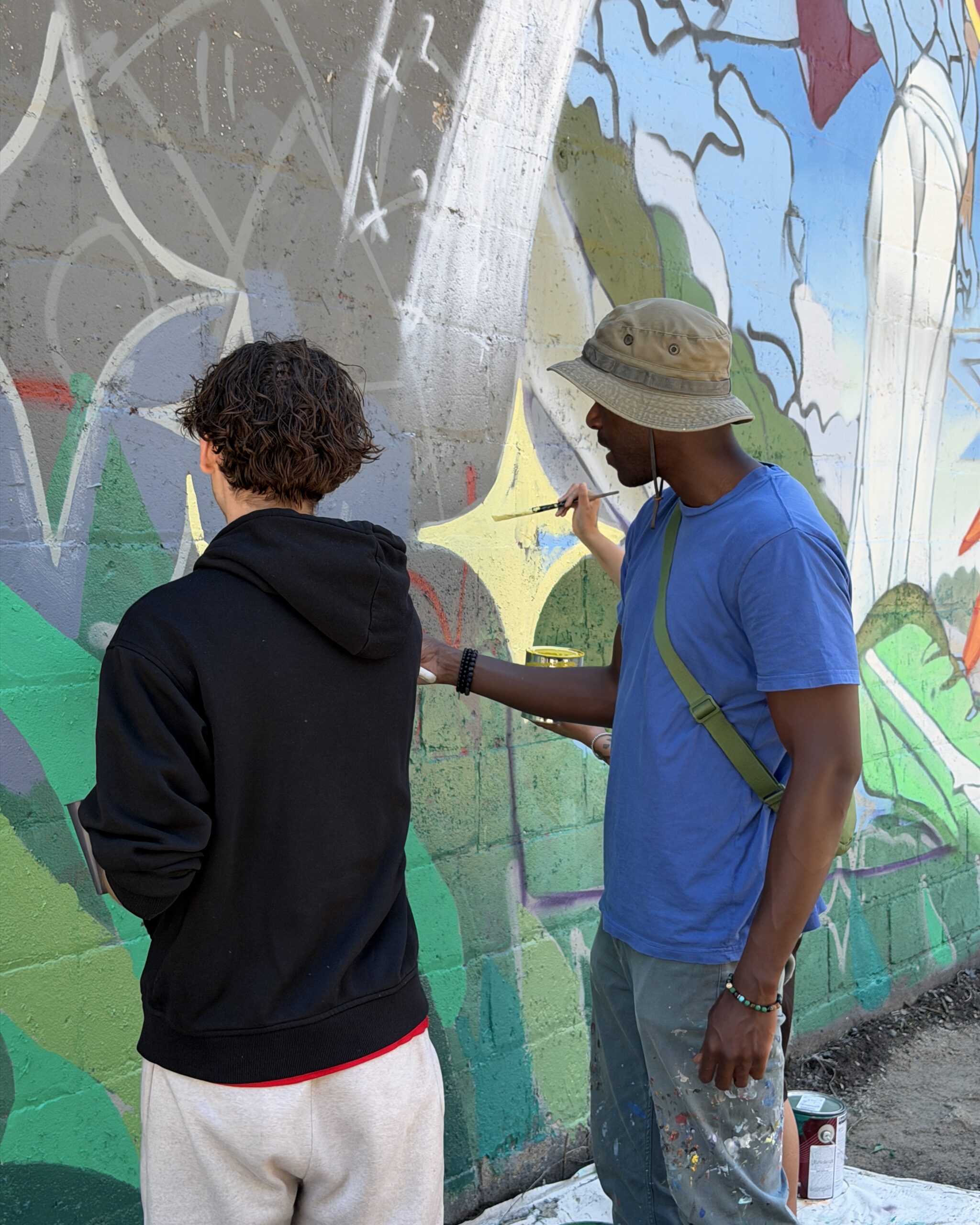 Artist Phillip Saunders at right with a community member painting the mural